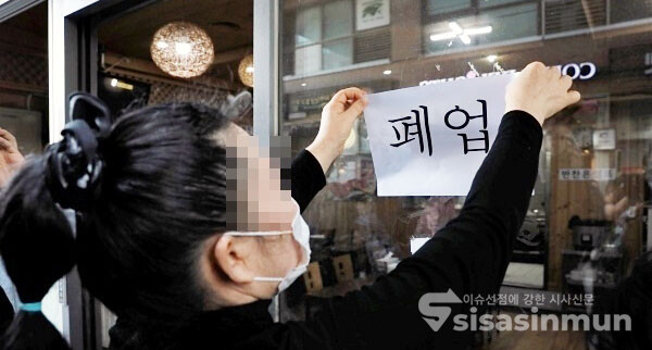 코로나 여파에 따른 폐업 소상공인이 폐업 안내문을 붙이고 있다. [사진 / 오훈 기자]